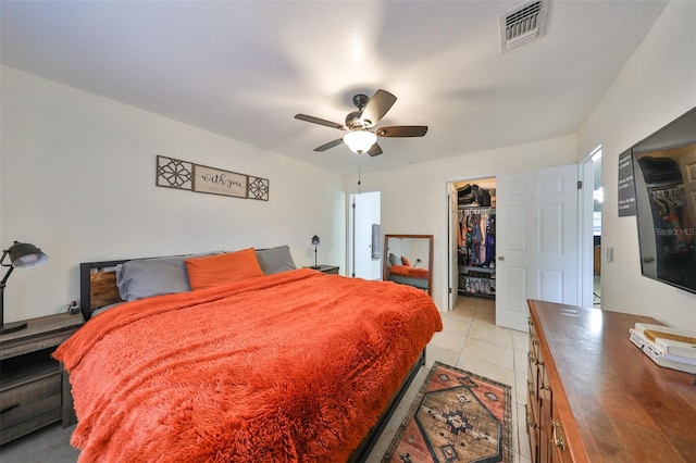 tiled bedroom featuring a closet, a spacious closet, and ceiling fan