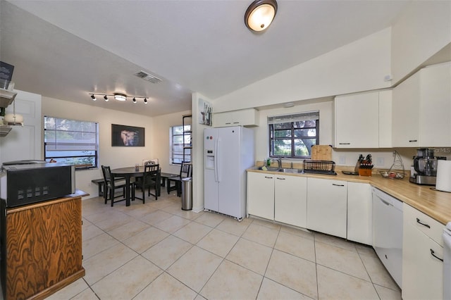 kitchen with white cabinets, light tile patterned floors, white appliances, and vaulted ceiling