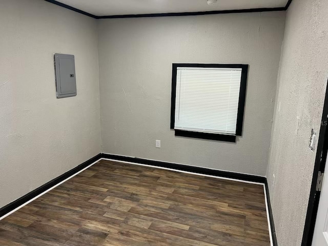 spare room featuring dark wood-type flooring, electric panel, and ornamental molding