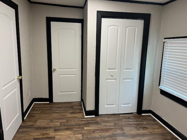 unfurnished bedroom with dark wood-type flooring, a closet, and crown molding