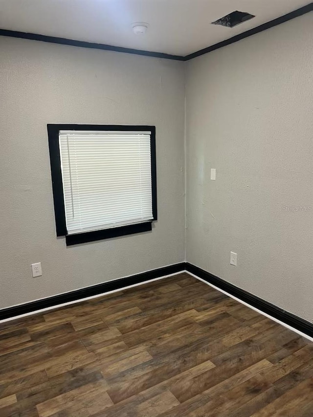 empty room with dark wood-type flooring and ornamental molding