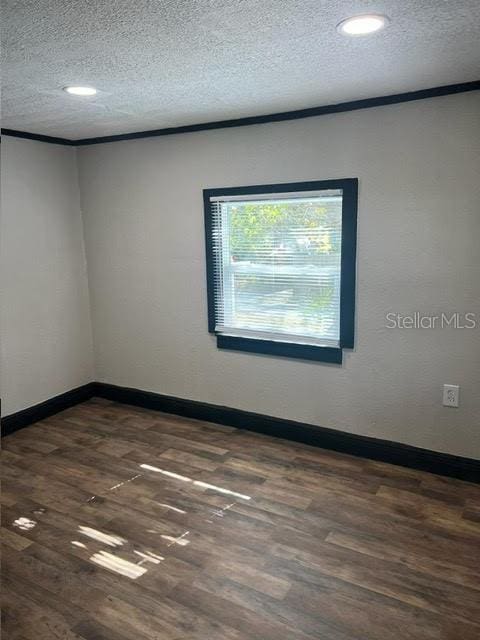 unfurnished room featuring a textured ceiling and dark hardwood / wood-style floors