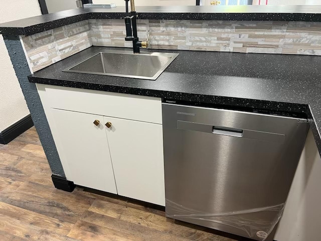 kitchen featuring dishwasher, hardwood / wood-style floors, sink, backsplash, and white cabinetry