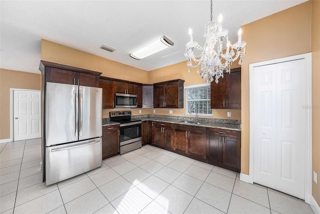 kitchen featuring hanging light fixtures, light tile patterned floors, appliances with stainless steel finishes, and a notable chandelier