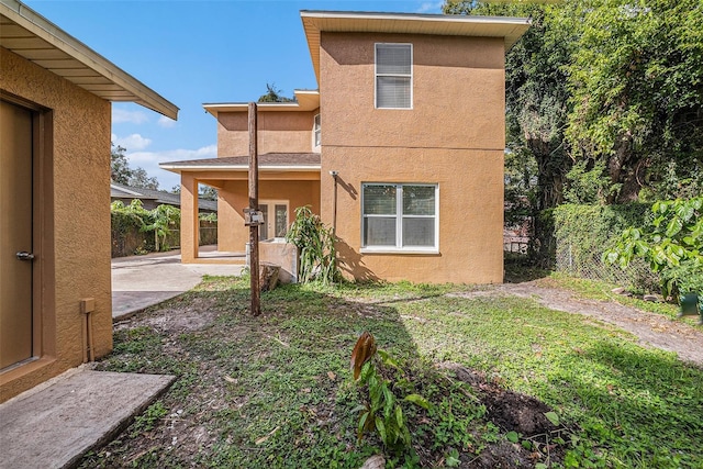 rear view of property featuring a lawn and a patio area