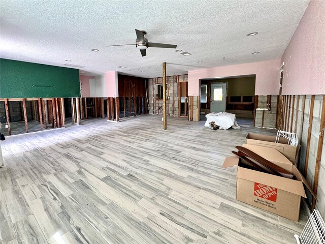 misc room with light hardwood / wood-style floors, ceiling fan, and a textured ceiling