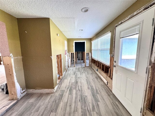 corridor with a textured ceiling and hardwood / wood-style flooring