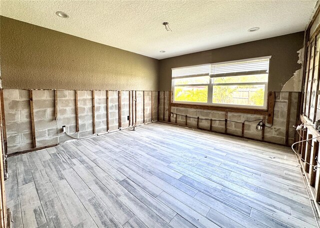 spare room featuring light wood-type flooring and a textured ceiling