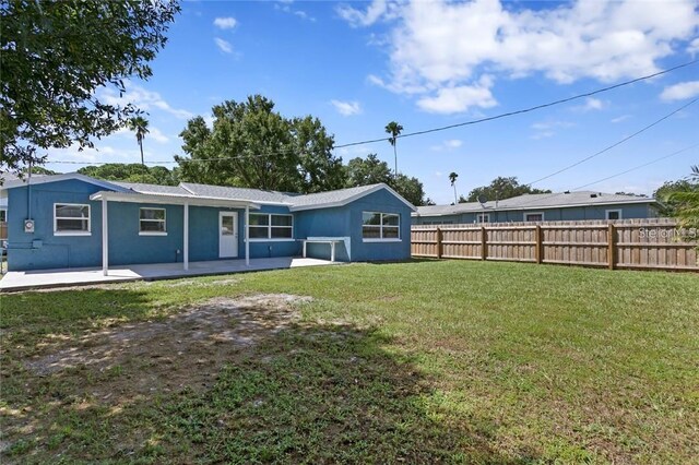 rear view of property featuring a patio and a lawn