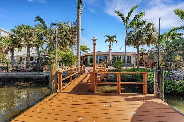 view of dock featuring a water view and fence