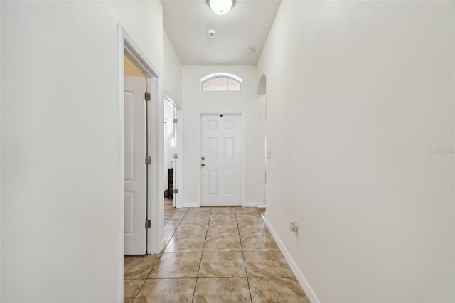 doorway featuring a towering ceiling and light tile patterned flooring