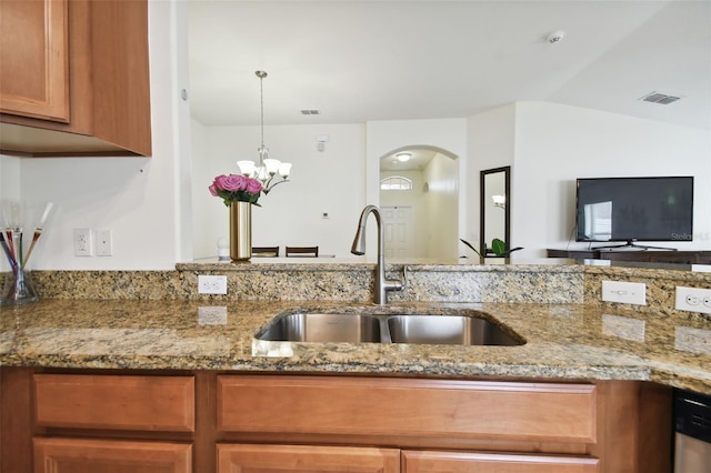 kitchen featuring light stone counters, a notable chandelier, sink, dishwasher, and lofted ceiling