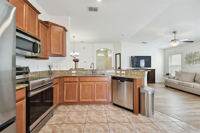 kitchen featuring stainless steel appliances, lofted ceiling, kitchen peninsula, sink, and light hardwood / wood-style flooring