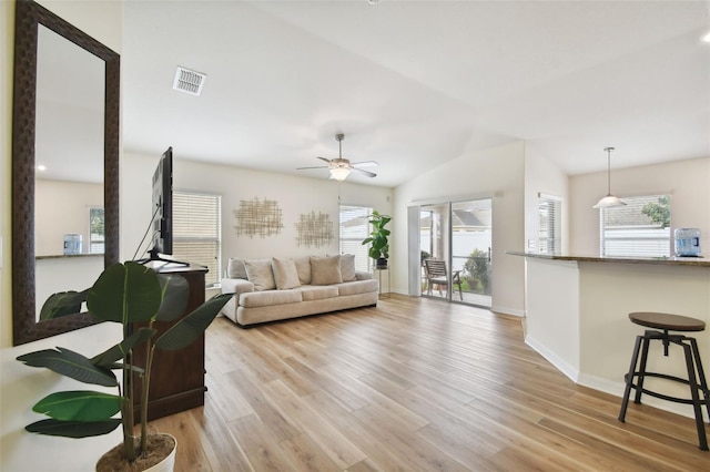 living room featuring light wood-type flooring, vaulted ceiling, ceiling fan, and a healthy amount of sunlight