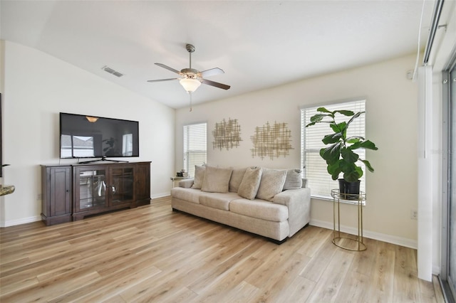 living room with a healthy amount of sunlight, light hardwood / wood-style flooring, and vaulted ceiling