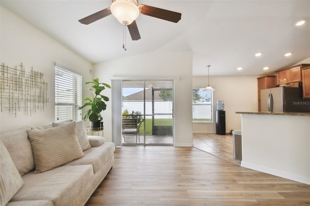 living room featuring vaulted ceiling, ceiling fan, and light hardwood / wood-style flooring