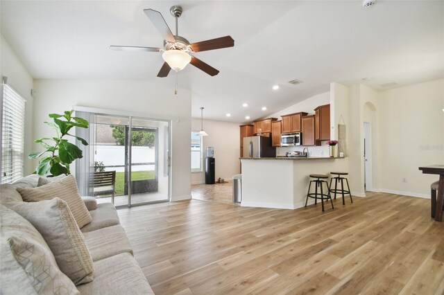 living room with ceiling fan, light wood-type flooring, and lofted ceiling