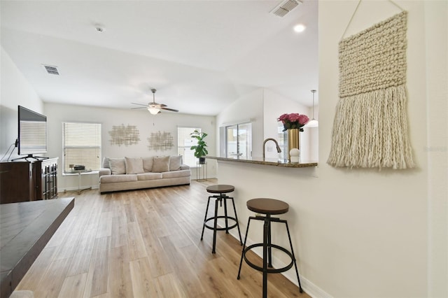 living room with ceiling fan, light hardwood / wood-style floors, lofted ceiling, and a healthy amount of sunlight