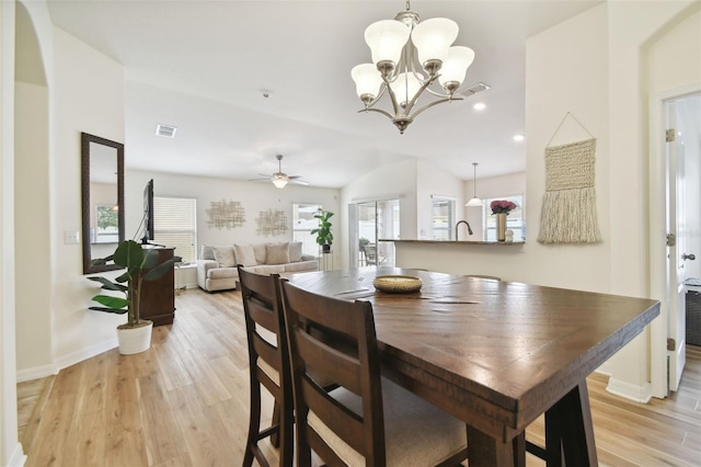 dining room featuring light wood-type flooring, ceiling fan with notable chandelier, and lofted ceiling