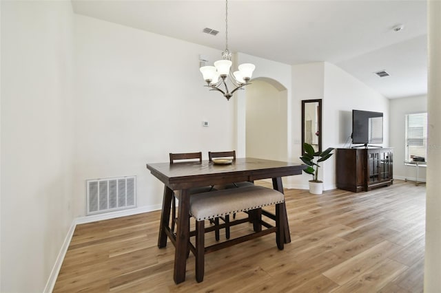 dining room featuring lofted ceiling, an inviting chandelier, and light hardwood / wood-style flooring