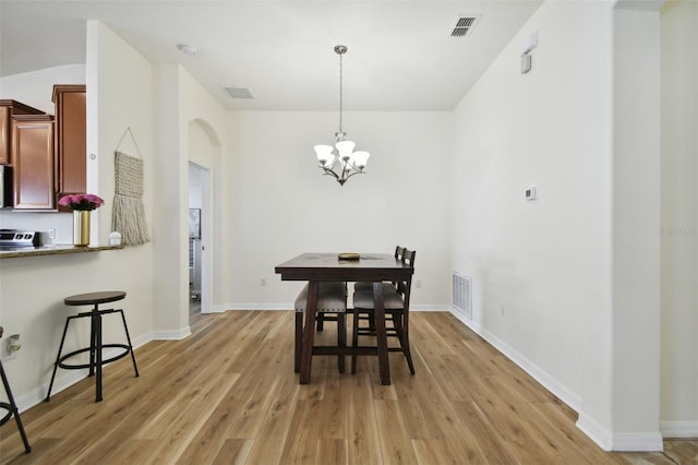 dining space with light wood-type flooring and a notable chandelier