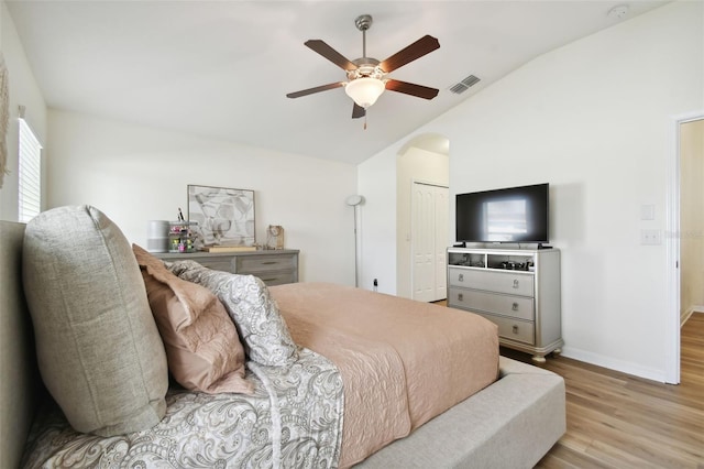 bedroom featuring lofted ceiling, ceiling fan, a closet, light wood-type flooring, and multiple windows