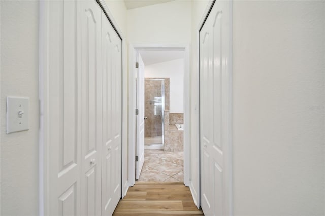 corridor with light hardwood / wood-style floors and lofted ceiling