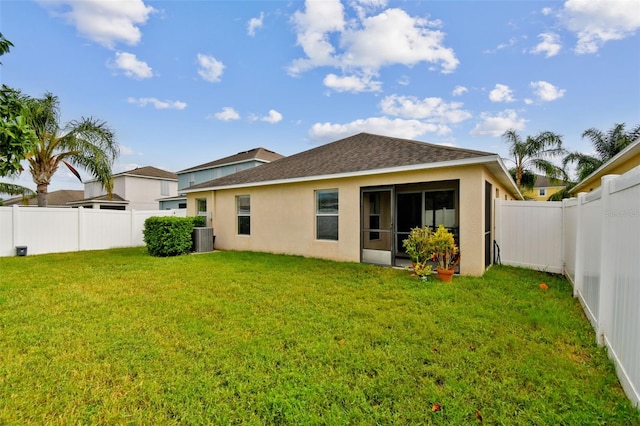 back of property with central AC unit and a yard