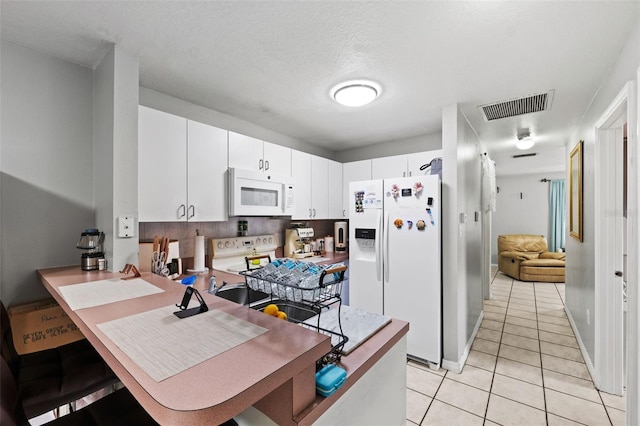 kitchen with white cabinetry, kitchen peninsula, a textured ceiling, light tile patterned floors, and white appliances