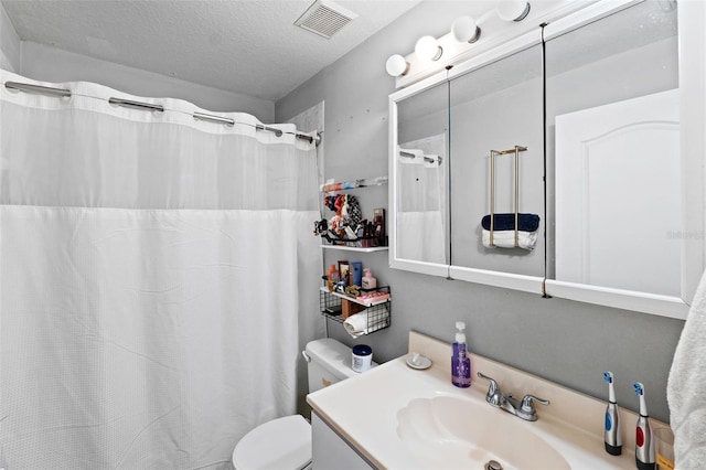 bathroom featuring vanity, a textured ceiling, and toilet