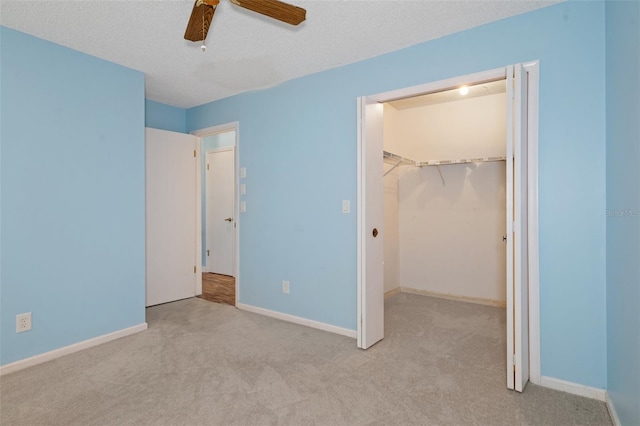 unfurnished bedroom featuring a textured ceiling, ceiling fan, light carpet, and a closet