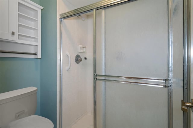 bathroom featuring toilet and a shower with door