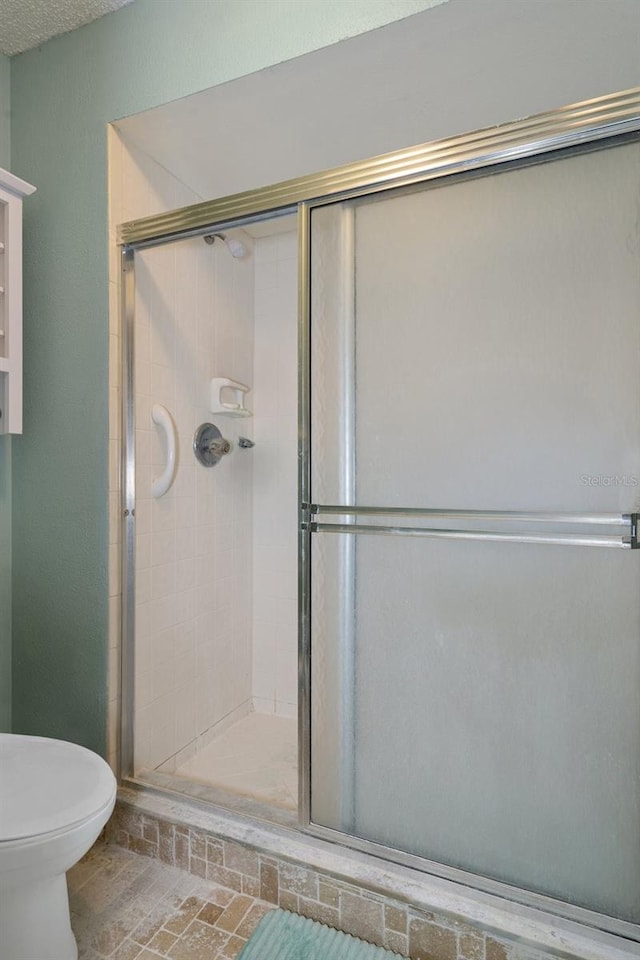 bathroom with toilet and a shower with door