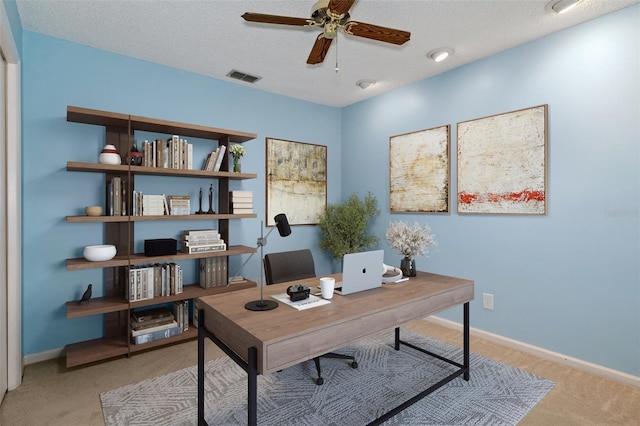 home office with ceiling fan, light colored carpet, and a textured ceiling