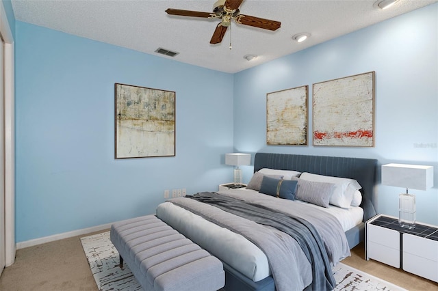 carpeted bedroom featuring ceiling fan and a textured ceiling