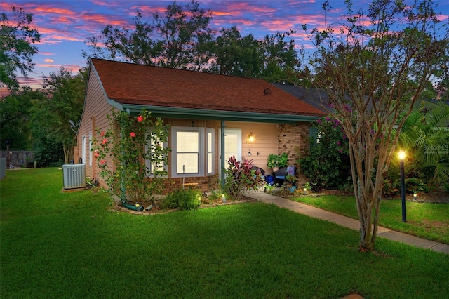 view of front facade with a lawn and central air condition unit