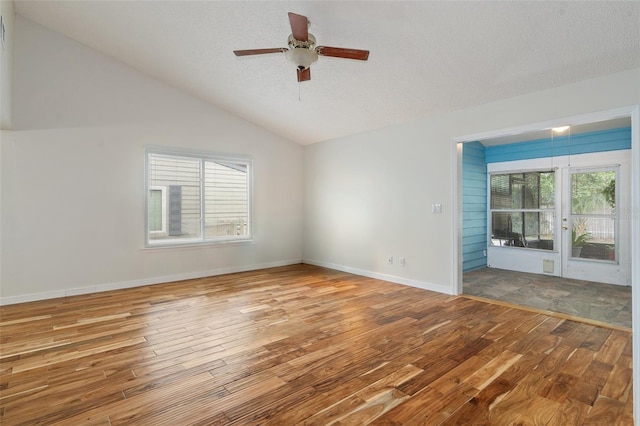 empty room featuring a textured ceiling, hardwood / wood-style flooring, ceiling fan, and lofted ceiling