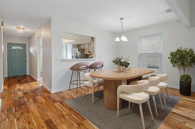 dining space featuring a chandelier, hardwood / wood-style floors, and a textured ceiling