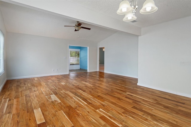 unfurnished living room with hardwood / wood-style flooring, lofted ceiling with beams, a textured ceiling, and ceiling fan with notable chandelier