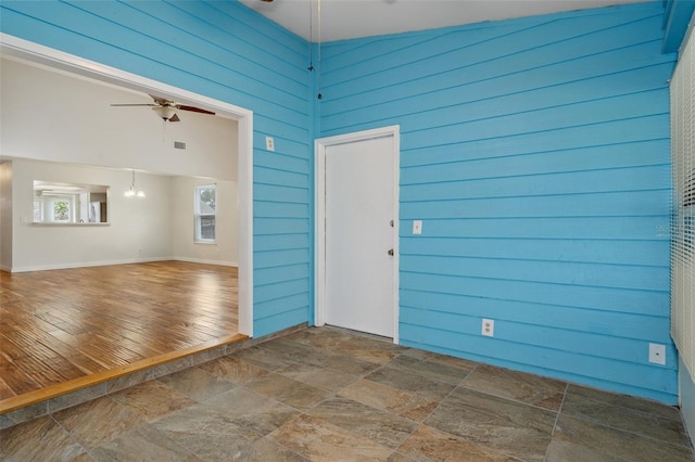 spare room with wood walls, high vaulted ceiling, dark wood-type flooring, and ceiling fan