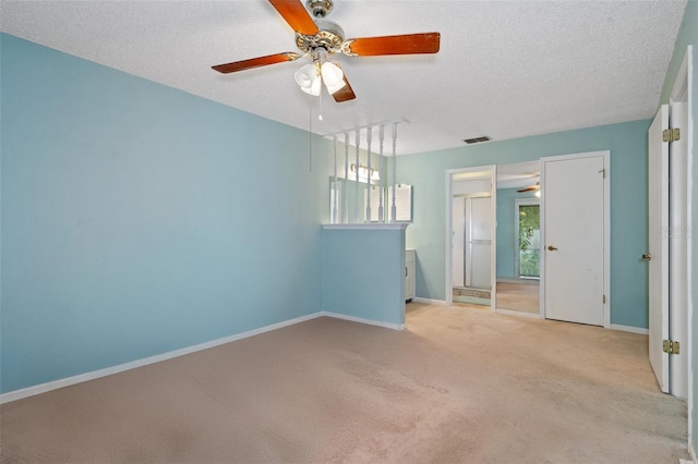 carpeted spare room featuring a textured ceiling, ceiling fan, and a healthy amount of sunlight