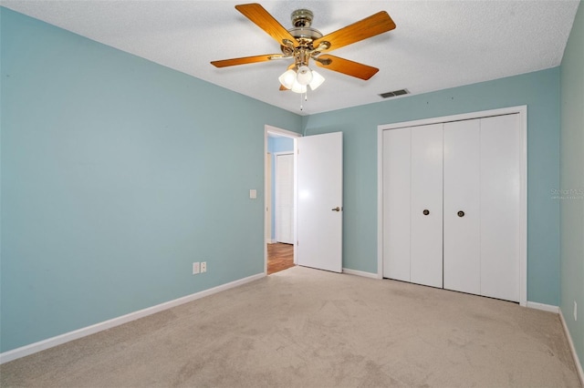 unfurnished bedroom with light carpet, a textured ceiling, a closet, and ceiling fan