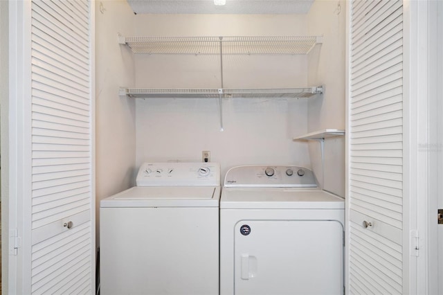 clothes washing area with washing machine and dryer and a textured ceiling