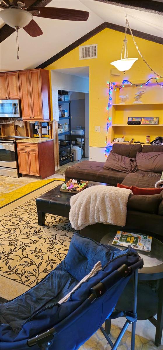 living room with vaulted ceiling, ornamental molding, and ceiling fan