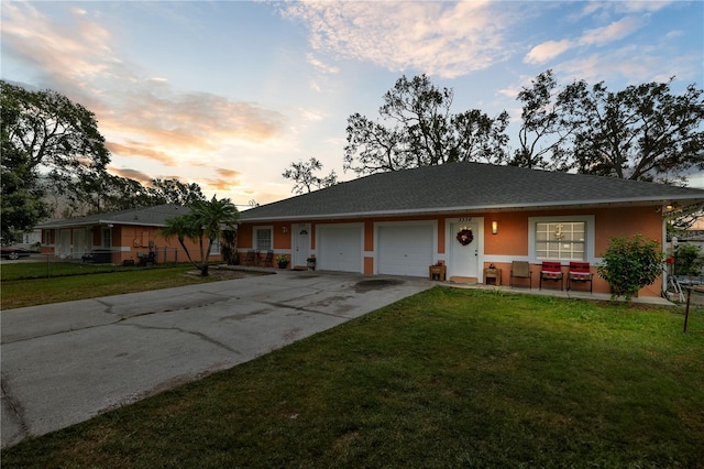 single story home featuring a garage and a yard