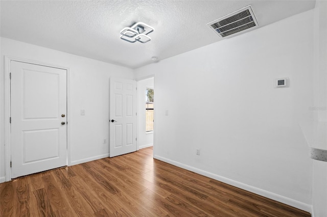 unfurnished room with hardwood / wood-style floors and a textured ceiling