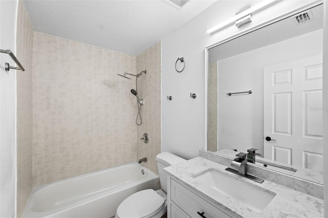 full bathroom with tiled shower / bath combo, vanity, a textured ceiling, and toilet