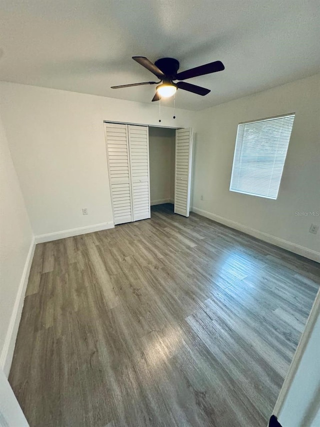 unfurnished bedroom featuring ceiling fan, a textured ceiling, a closet, and wood-type flooring