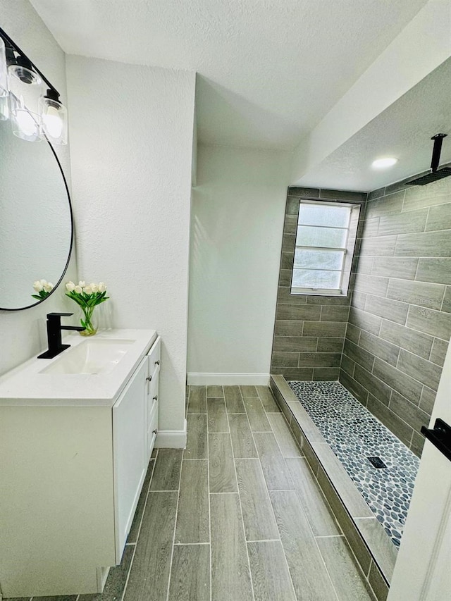 bathroom featuring vanity, a textured ceiling, and tiled shower