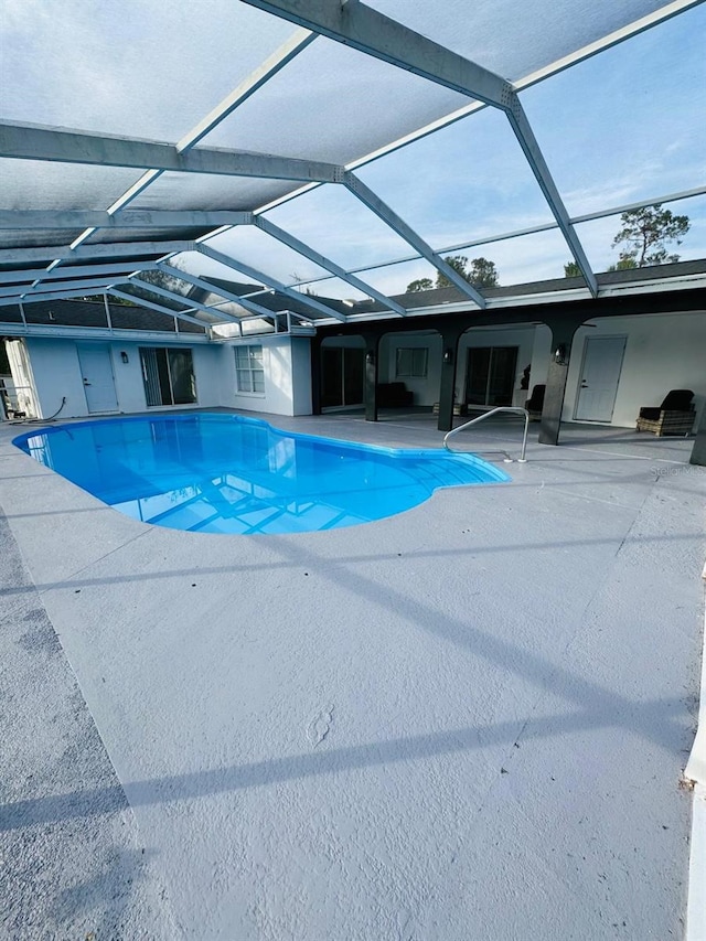 view of swimming pool featuring glass enclosure and a patio